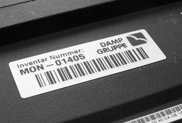 Ein Barcodeschild mit Firmenlogo, Barcode und Inventarnummer